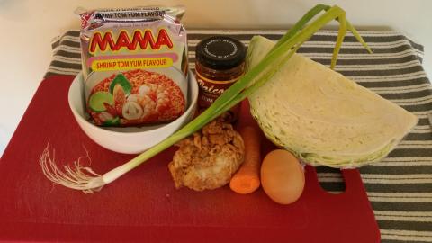 Raw ingredients: instant noodles, a jar of Tom Yum paste, spring onion, cabbage, carrot, egg, and a piece of fried chicken.