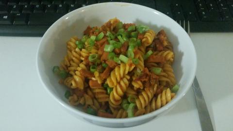 A bowl of pasta, garnished with spring onion.