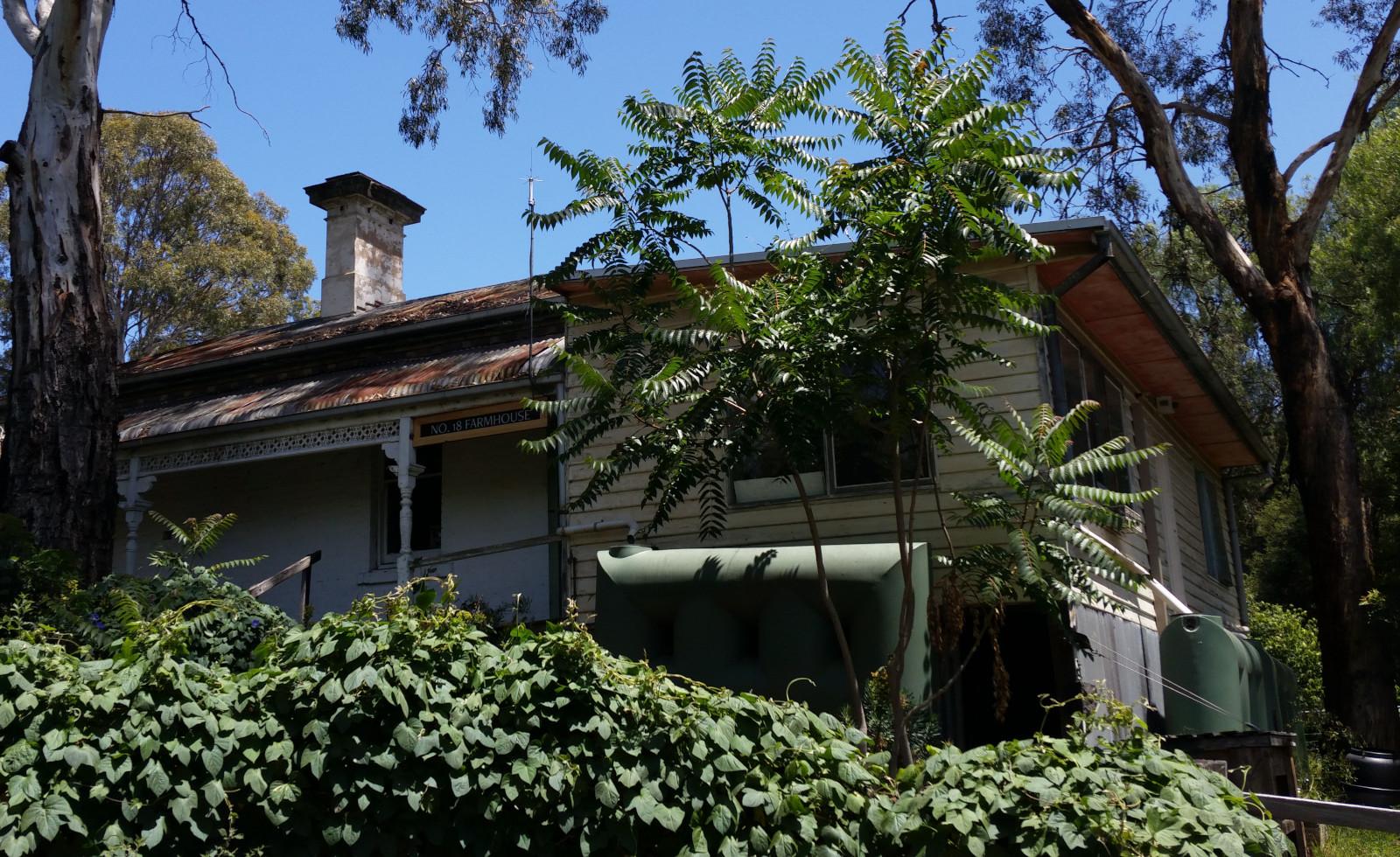 "No. 18 Farmhouse", an elevated shack which looks to be an original brick structure with a later aluminium-clad fibro addition. Brick chimney, rusting corrugated iron roof, bull-nose verandah, and a couple of very recent plastic rainwater collection tanks on adjacent sides of the house.